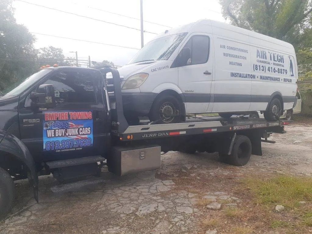 A white Air Tech cargo van sits loaded on an Empire Towing flatbed